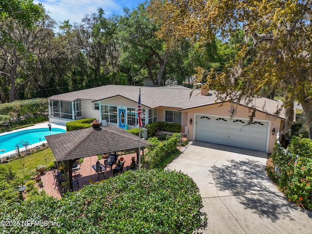 50 SE Forest St, Keystone Heights, FL 32656 - view of front of property with a sunroom, a garage, concrete driveway, stucco siding, and an outdoor pool