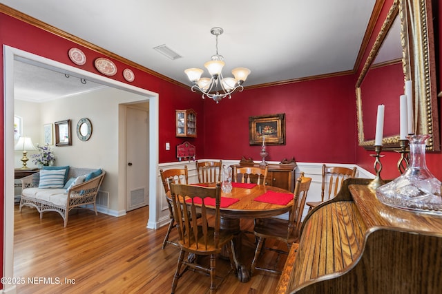 50 SE Forest St, Keystone Heights, FL 32656 - dining space with wood finished floors, an inviting chandelier, ornamental molding, and visible vents