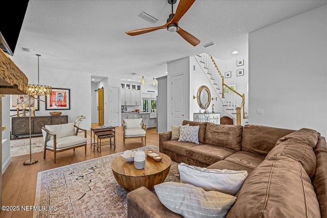 900 White St, Fernandina Beach, FL 32034 - living room with a ceiling fan, light wood-style flooring, stairway, a textured ceiling, and a chandelier