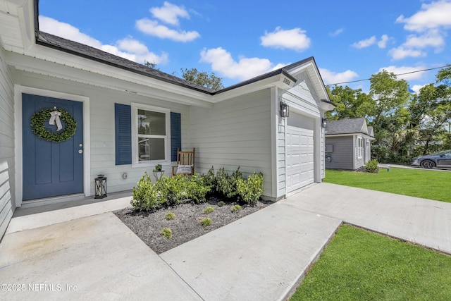 entrance to property with a yard, covered porch, a garage, and concrete driveway