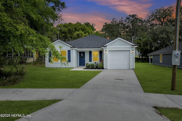 ranch-style house featuring a garage, a yard, roof with shingles, and driveway