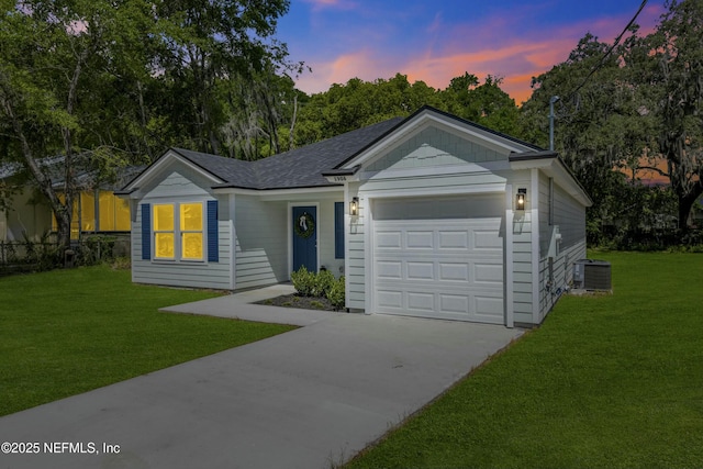 ranch-style home featuring a lawn, central air condition unit, driveway, and an attached garage