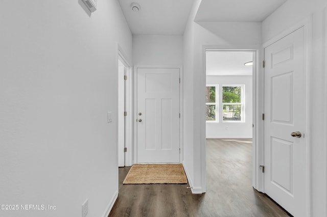 hall featuring dark wood-type flooring and baseboards