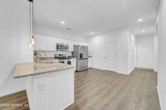 kitchen with light stone counters, light wood-style flooring, white cabinets, stainless steel appliances, and a sink