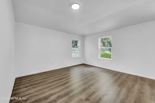 unfurnished room with baseboards and dark wood finished floors