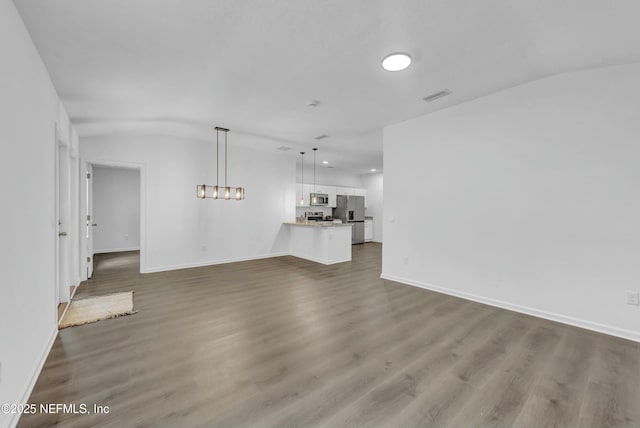 unfurnished living room with visible vents, baseboards, vaulted ceiling, and dark wood-style floors