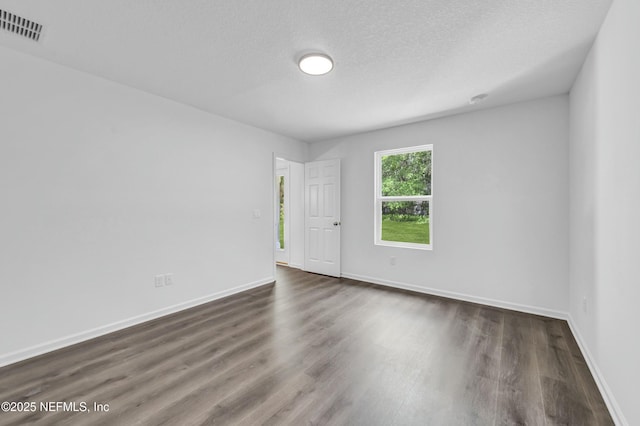 unfurnished room featuring visible vents, baseboards, a textured ceiling, and dark wood finished floors