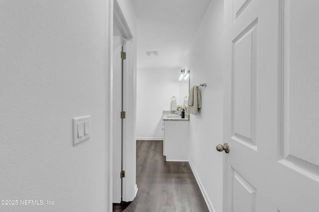 hallway featuring dark wood-style flooring and baseboards