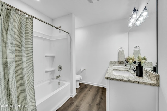 full bathroom with toilet, wood finished floors, shower / tub combo, double vanity, and baseboards