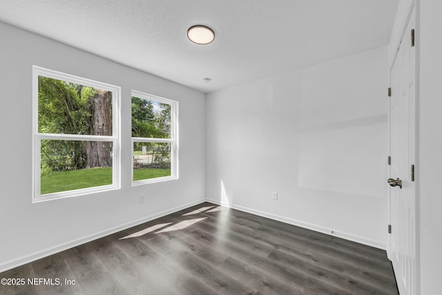 empty room featuring dark wood-style flooring, baseboards, and a textured ceiling
