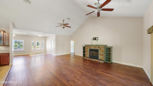 unfurnished living room with baseboards, a fireplace, visible vents, ceiling fan, and wood finished floors