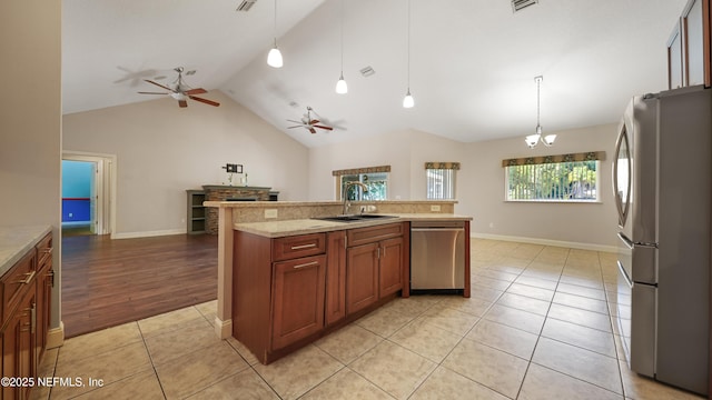 kitchen featuring light countertops, lofted ceiling, stainless steel appliances, ceiling fan with notable chandelier, and a sink