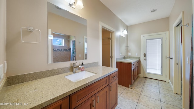 bathroom with tile patterned floors, two vanities, a sink, and walk in shower