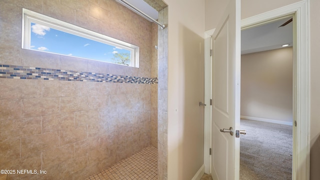 full bath featuring baseboards and tiled shower
