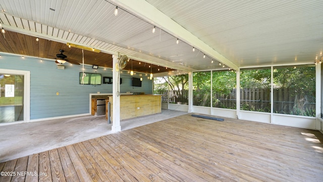 unfurnished sunroom with track lighting, ceiling fan, and outdoor wet bar