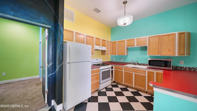 kitchen featuring white appliances, under cabinet range hood, visible vents, a sink, and light brown cabinetry