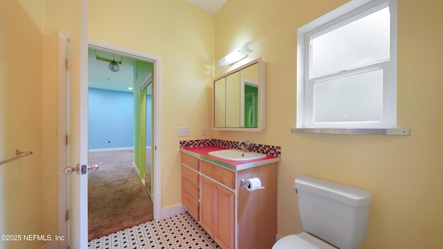 bathroom with toilet, vanity, and baseboards