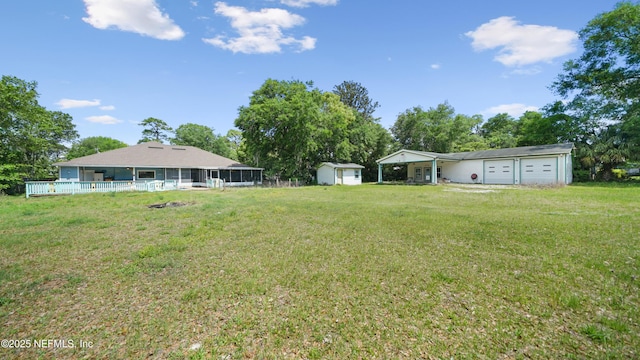 view of yard with a storage shed, an outdoor structure, a sunroom, and a garage
