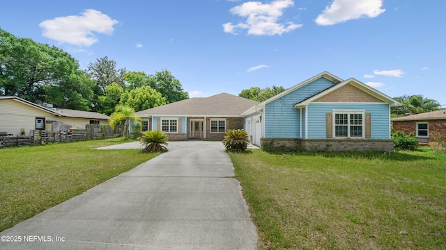 view of front of property featuring a front yard, an attached garage, fence, brick siding, and driveway