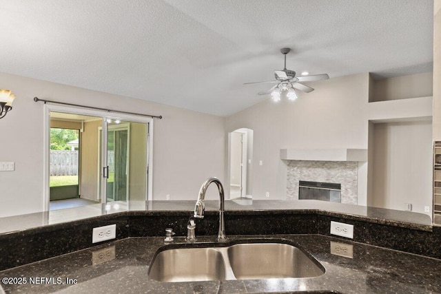 1029 Buttercup Dr, Saint Johns, FL 32259 - kitchen with a sink, vaulted ceiling, dark stone counters, a ceiling fan, and a premium fireplace