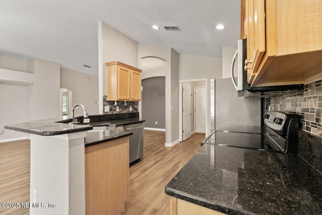 1029 Buttercup Dr, Saint Johns, FL 32259 - kitchen with stainless steel appliances, a sink, arched walkways, a peninsula, and light brown cabinetry