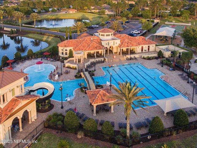 community pool featuring fence, a water view, and a patio area
