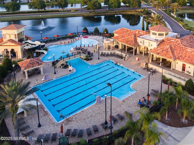 community pool featuring a water slide, a water view, a gazebo, and a patio