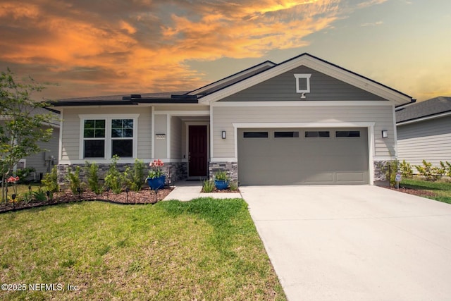 view of front of property featuring concrete driveway, a yard, a garage, and stone siding