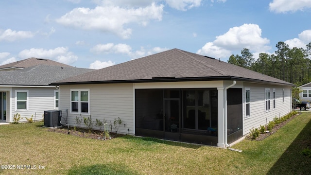 rear view of property featuring a shingled roof, central AC unit, and a lawn