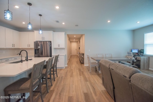 living area featuring visible vents, baseboards, recessed lighting, and light wood-style floors