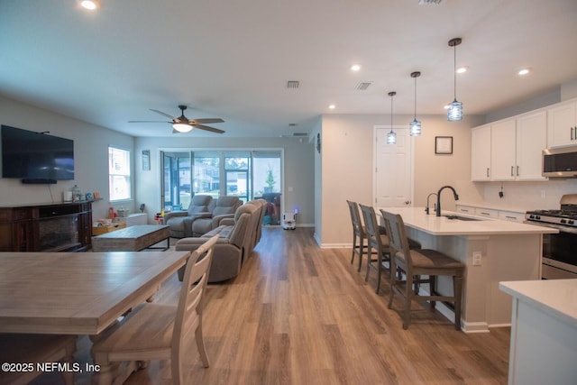 kitchen with visible vents, white cabinets, light countertops, a kitchen island with sink, and stainless steel appliances