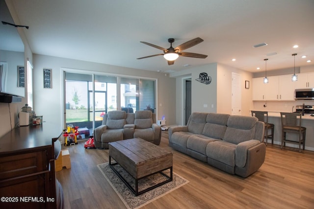 living area featuring wood finished floors, a ceiling fan, visible vents, and recessed lighting