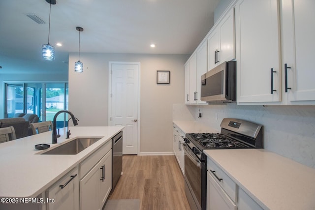 kitchen featuring light wood-style flooring, white cabinetry, visible vents, appliances with stainless steel finishes, and a sink