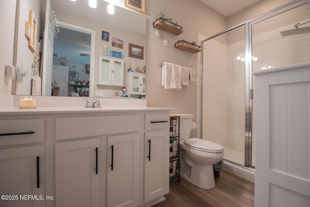 bathroom featuring toilet, a shower stall, vanity, and wood finished floors