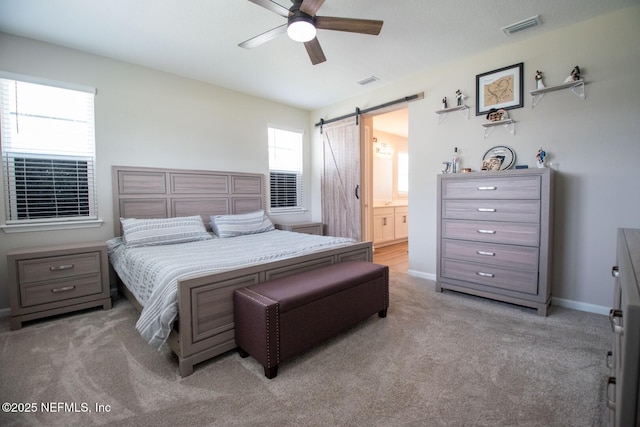 bedroom featuring light carpet, a barn door, visible vents, and baseboards