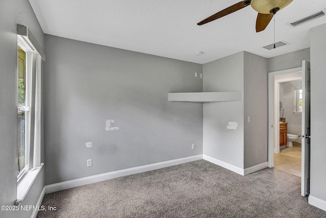 carpeted empty room with visible vents, a ceiling fan, and a healthy amount of sunlight