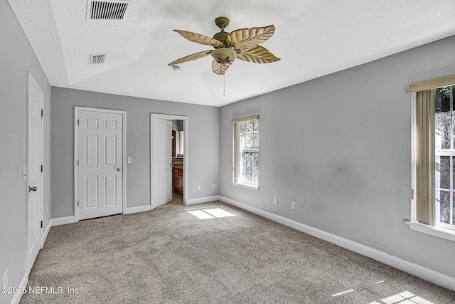 unfurnished bedroom with a textured ceiling, baseboards, carpet, and visible vents