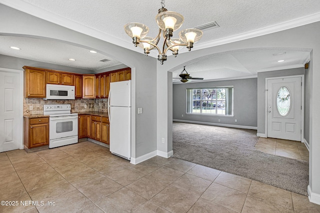 kitchen with arched walkways, white appliances, light colored carpet, and a textured ceiling