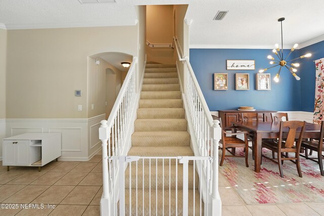 13738 Harbor Creek Pl, Jacksonville, FL 32224 - staircase featuring ornamental molding, tile patterned flooring, visible vents, wainscoting, and arched walkways