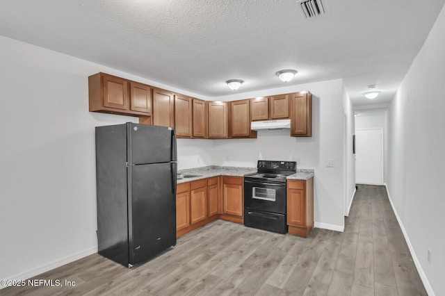 1354 Crestwood St, Jacksonville, FL 32208 - kitchen with under cabinet range hood, light stone countertops, light wood-style floors, visible vents, and black appliances