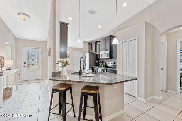 116 Timberwood Dr, Saint Augustine, FL 32084 - kitchen with a breakfast bar, stainless steel appliances, a sink, dark stone counters, and arched walkways