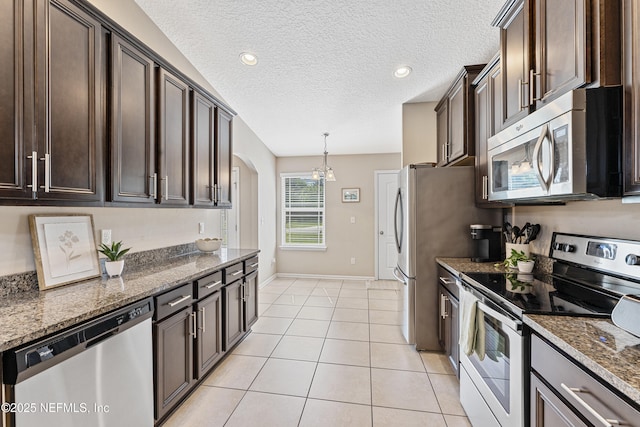116 Timberwood Dr, Saint Augustine, FL 32084 - kitchen with stainless steel appliances, dark brown cabinets, dark stone counters, a chandelier, and light tile patterned flooring