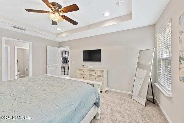 116 Timberwood Dr, Saint Augustine, FL 32084 - bedroom with a raised ceiling, light carpet, baseboards, ensuite bathroom, and a ceiling fan