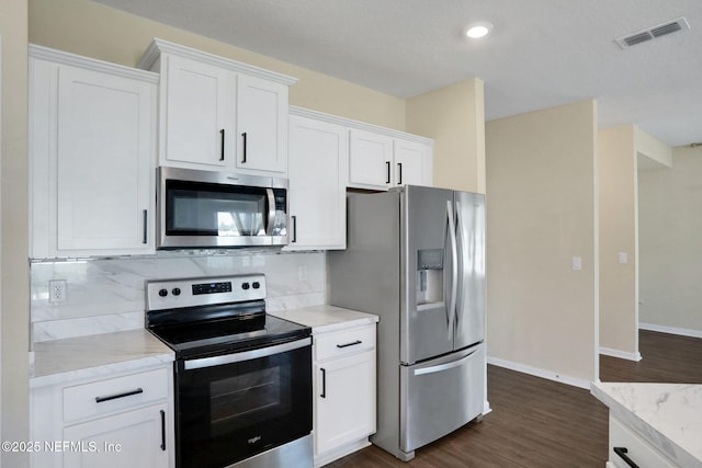 2351 Oak Stream Dr, Green Cove Springs, FL 32043 - kitchen with visible vents, dark wood-style flooring, white cabinetry, stainless steel appliances, and decorative backsplash