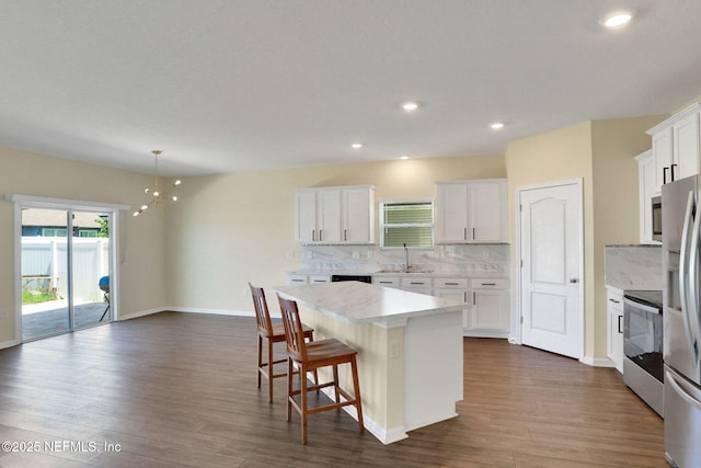 2351 Oak Stream Dr, Green Cove Springs, FL 32043 - kitchen with a center island, light countertops, appliances with stainless steel finishes, dark wood finished floors, and decorative backsplash