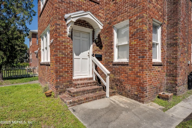 2649 Dellwood Ave, Jacksonville, FL 32204 - view of exterior entry featuring a lawn, fence, and brick siding