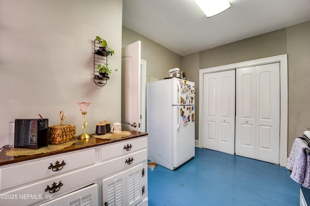 2649 Dellwood Ave, Jacksonville, FL 32204 - kitchen with wood finished floors, white cabinets, freestanding refrigerator, and dark countertops