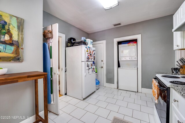 2649 Dellwood Ave, Jacksonville, FL 32204 - kitchen featuring freestanding refrigerator, white cabinets, visible vents, range with electric stovetop, and stacked washing maching and dryer