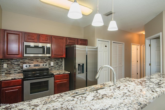 8235 Lobster Bay Ct Unit 305, Jacksonville, FL 32256 - kitchen featuring appliances with stainless steel finishes, reddish brown cabinets, backsplash, and visible vents