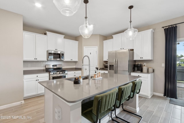 75743 Spoonbill Ln, Yulee, FL 32097 - kitchen featuring baseboards, a sink, appliances with stainless steel finishes, wood finish floors, and a center island with sink
